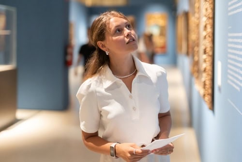 Jonge vrouw leest een informatiebord in een museum